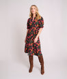 Model is wearing UNTUCKit Short Sleeve Fall Floral Midi Alix Dress in Black Orange Pink Floral Print.