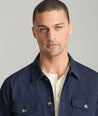 Model is wearing UNTUCKit chadwick herringbone over shirt in navy. 