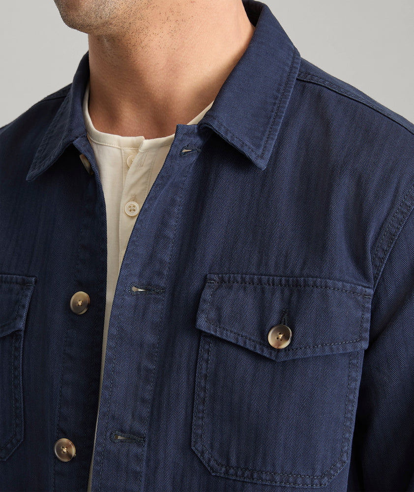 Model is wearing UNTUCKit chadwick herringbone over shirt in navy. 