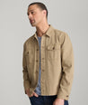 Model is wearing UNTUCKit chadwick herringbone over shirt in tan. 