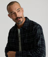 Model is wearing UNTUCKit Chaselo in bark green and black check over shirt.