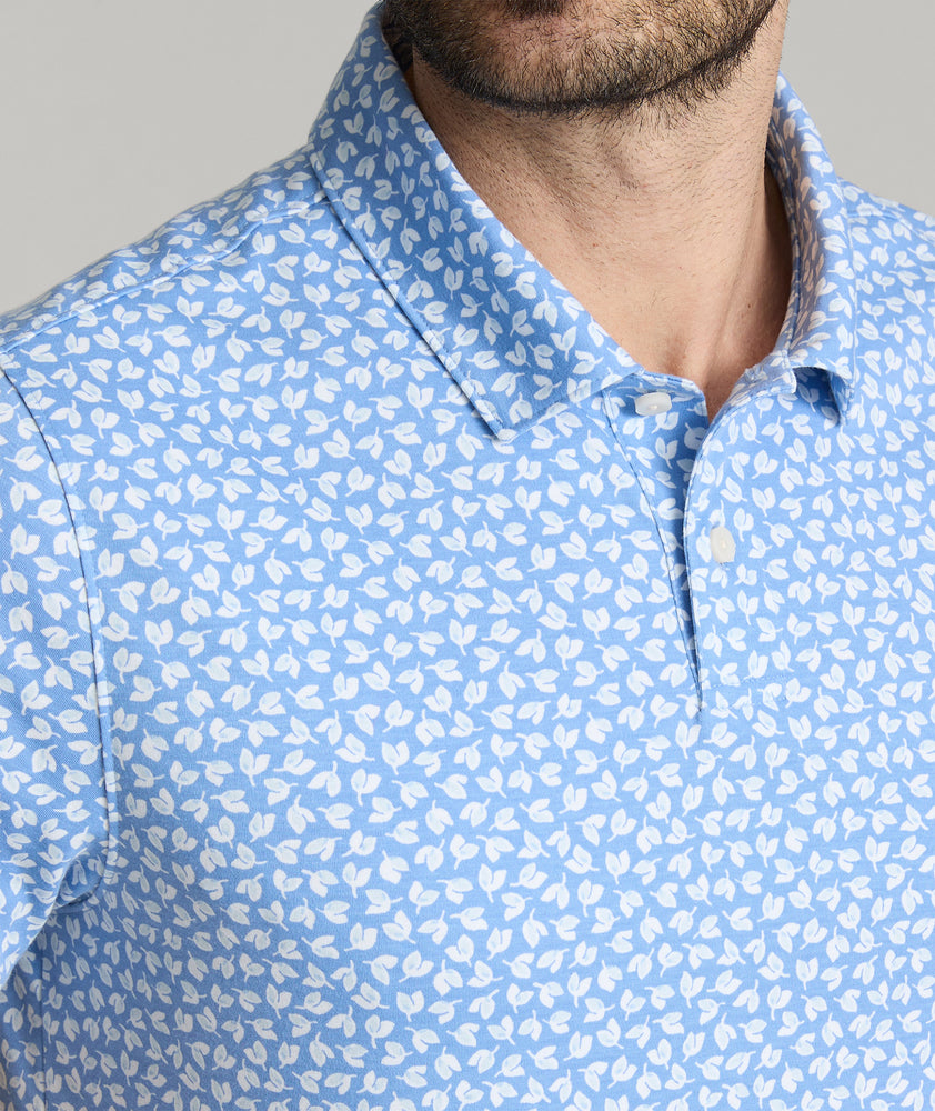 Model is wearing UNUCKit George printed wrinkle-free polo in ultramarine. 