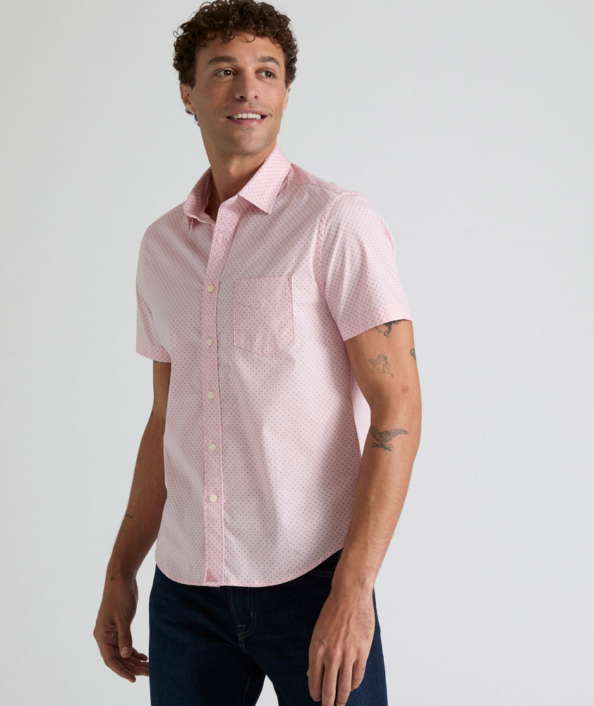 Model is wearing UNTUCKit Ingram short sleeve shirt in pink mini circle print. 