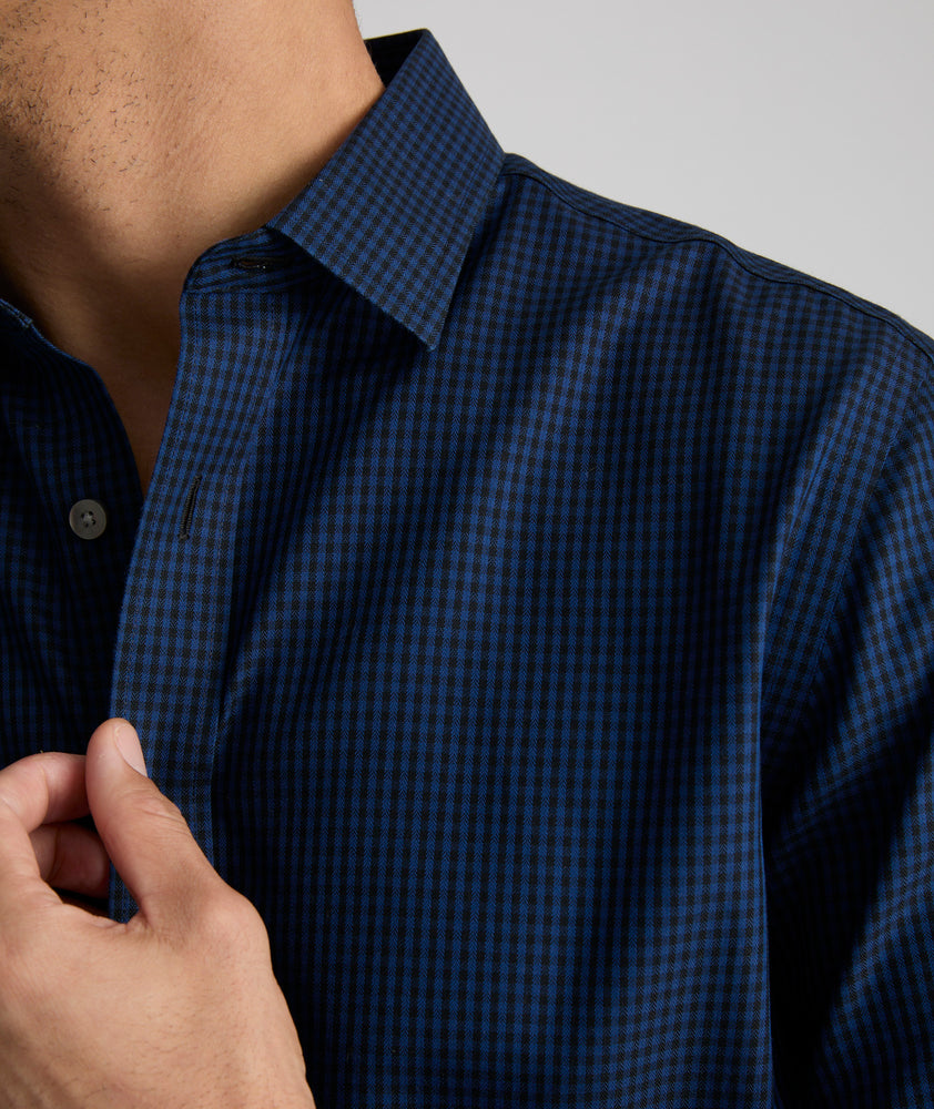 Model is  wearing UNTUCKit Johnston wrinkle-free shirt in navy and blue gingham.