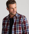 Model is wearing UNTUCKit Larson flannel in maroon grounded blue plaid. 