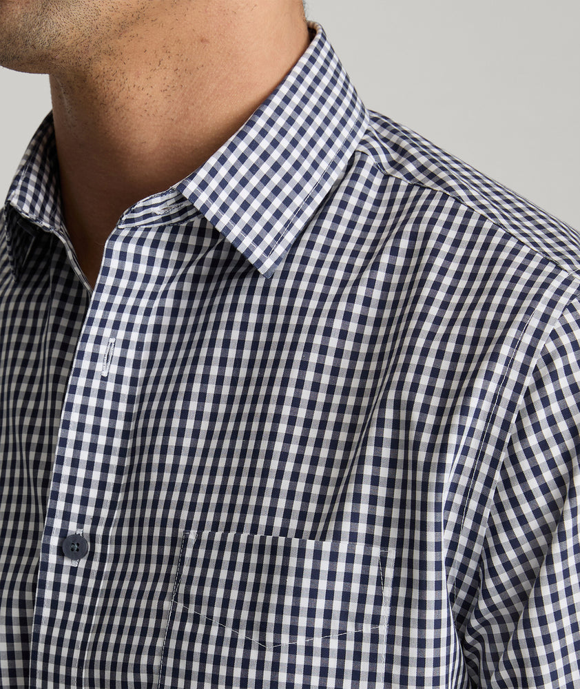 Model is wearing UNTUCKit Lawrence wrinkle free in navy blue gingham. 