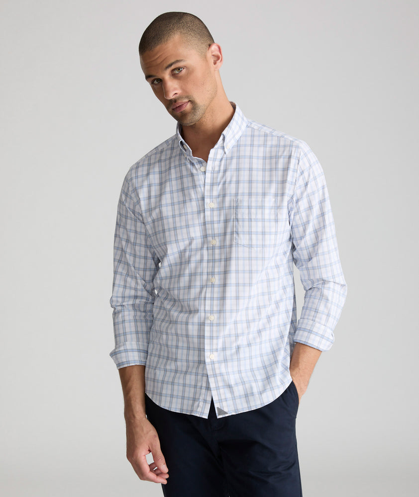 Model is wearing UNTUCKit Phillips performance shirt in white grounded with light blue and gray check. 