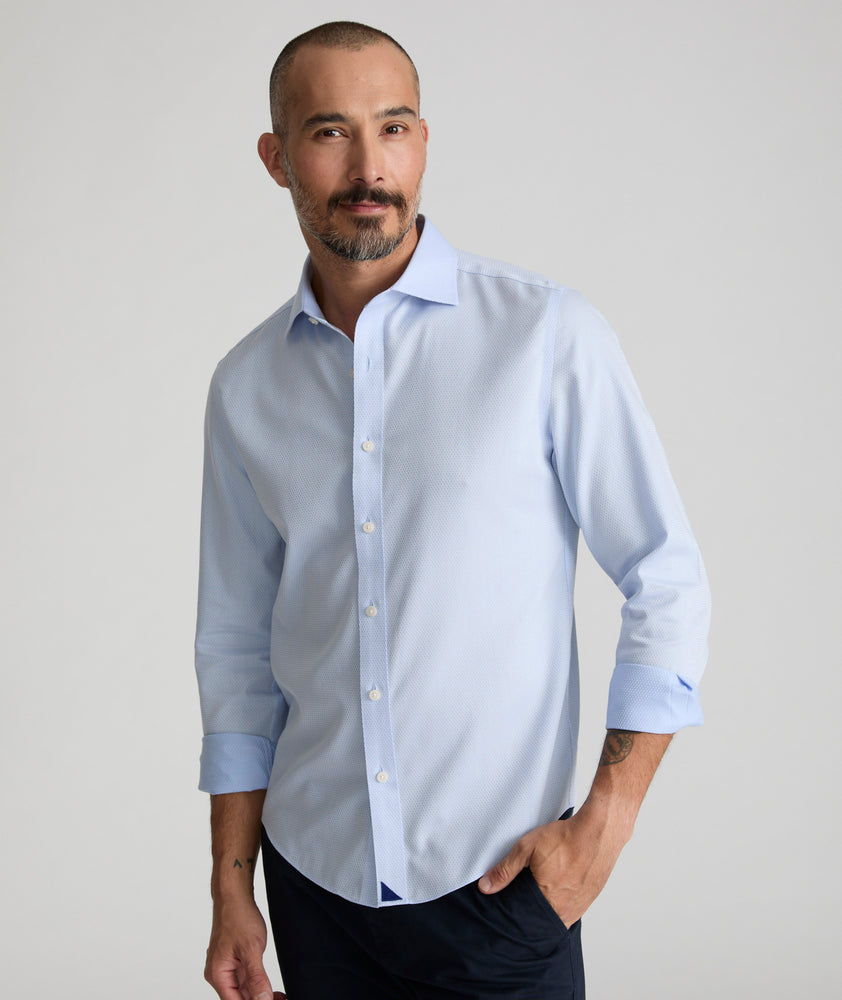 Model is wearing UNTUCKIt Richards wrinkle-free shirt in. light blue dobby print. 