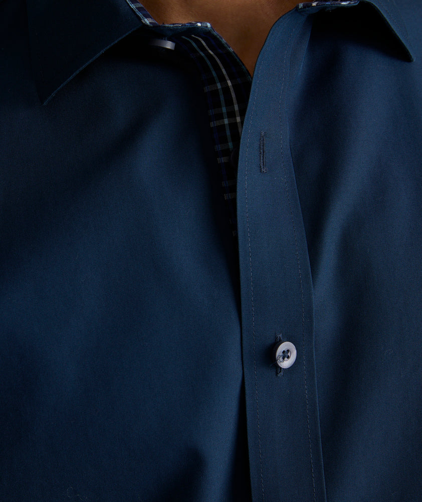 Model is wearing UNTUCKit Roberts wrinkle-free shirt in solid navy with blue check contrast cuff. 