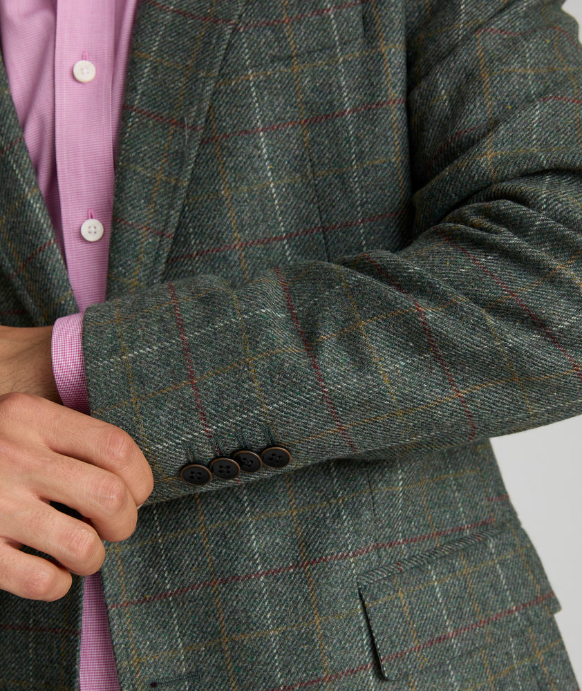 Model is wearing UNTUCKit Italian Wool Windsteig Sport Coat in Olive & Multicolor Windowpane.