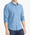 Model is wearing UNTUCKit Light Blue & Navy Gingham Wrinkle-Free Mariano Shirt. 